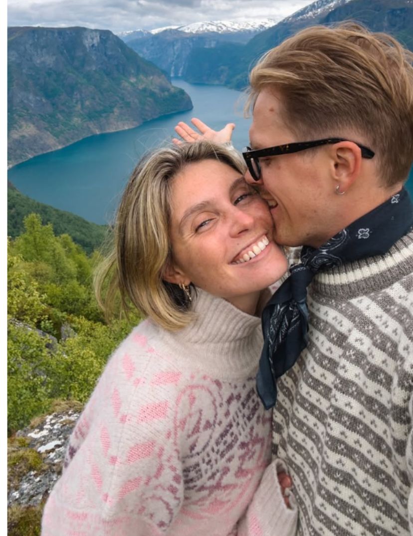 Elias og Kajsa smilende til kamera fra en fjelltopp i Norge med gensere fra Dale of Norway